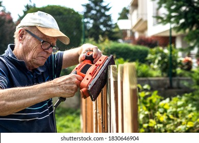 Verschwende in den Händen. Hochrangiger Mann, der im Garten einen Holzzaun singt. alter Tischler mit Elektrowerkwerkzeug