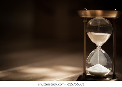 Sandglass, hourglass or egg timer on wooden floor with shadow showing the last second or last minute or time out. With copy space.