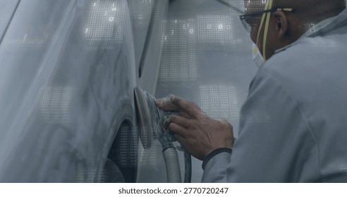 Sanding tech using sander on primed fender in bay, wearing respirator and coveralls, copy space. Autobody, panel, primer, workshop, orbital, dust, ventilation