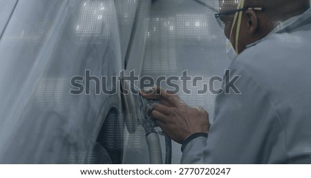 Sanding tech using sander on primed fender in bay, wearing respirator and coveralls, copy space. Autobody, panel, primer, workshop, orbital, dust, ventilation