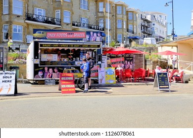 Sandown, Isle of Wight, UK. June 21, 2018. Holidaymakers enjoying food and drink at a mobile kiosk with a well known name on the promenade at Sandown on the Isle of Wight, UK.