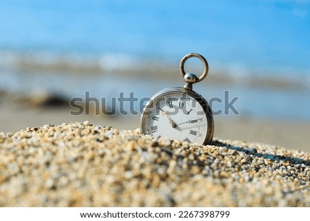 Sands of time. Antique pocket watch lost in the sand on the beach.