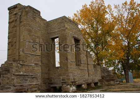 Sandstone blocks left standing from the second general hospital in Calgary, Alberta, Canada which was built in 1894 with Autumn foliage indicating seasonal change and time passages.