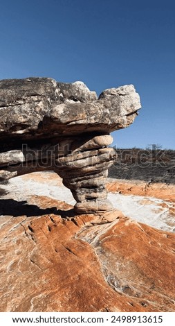 a sandstone formation that eroded the inside of the rock leaving a sculpure and pilling rocks in a rivebed surrounded by sand