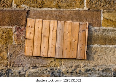 Sandstone Wall With Basement Window And Shaft For Potato Or Coal Cellar, Covered With Board Of Wooden Panels, Close-up