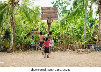 Sandugan, Siquijor, Philippines - May 13 2013: Three Kids Playing Basketball At Sand Field With Old Wooden Basketball Basket