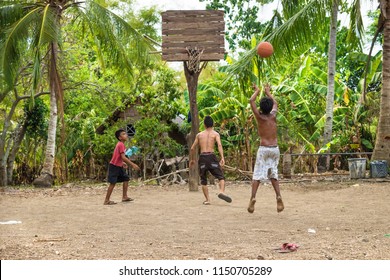 Sandugan, Siquijor, Philippines - May 13 2013: Three Kids Playing Basketball With One Kid Jumping At Sand Field With Old Wooden Basketball Basket