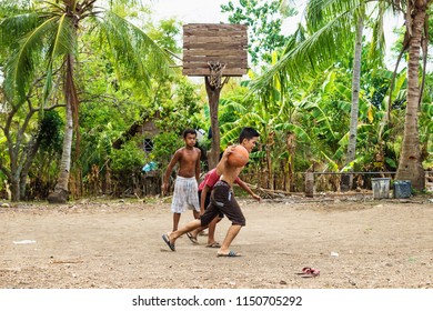 Sandugan, Siquijor, Philippines - May 13 2013: Three Kids Playing Basketball On Flip Flops At Sand Field With Old Wooden Basketball Basket