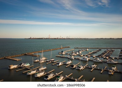 Sandusky, OH - October 17th, 2020:  The boat harbor and the rollercoasters at Cedar Point sit quietly early on a sunny day in the calm waters of Lake Erie.