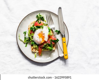 Sandwich with avocado, green salad, smoked salmon and poached egg on a light background, top view. Delicious healthy nutritious breakfast, brunch             