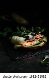 sandwich with avocado red fish cucumber on dark background