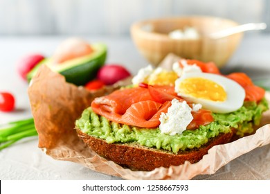 sandwich with avocado and salmon, green onions and gluten-free grain bread, radishes and tomatoes. concept diet food, copy space, sandwich take away, healthy fast food