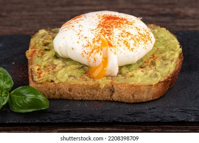 Sandwich With Avocado, Tomato And Poached Egg Yolk Flowing Out.