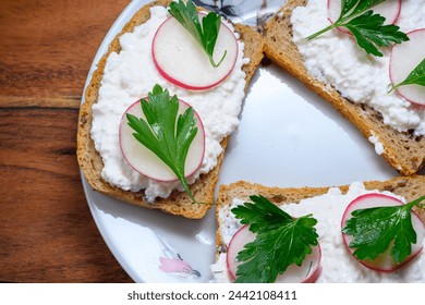 Sandwich with black bread, cottage cheese, radishes and parsley on white plate and wooden board - Powered by Shutterstock