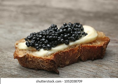 Sandwich with black caviar on wooden background
