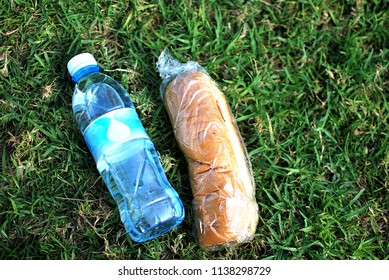 A Sandwich And A Bottle Of Water Lie On The Green Grass