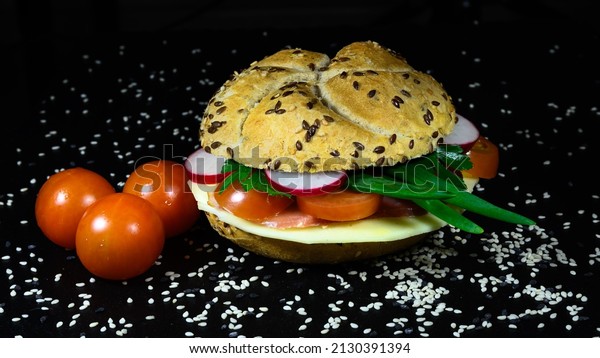 Sandwich, burger with fresh\
vegetables, cheese, ham, radish, onion leaves, plum tomatoes,\
seven-grain bread. Breakfast, lunch at work. Healthy food,\
saturated food.