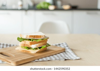 Sandwich with cheese and ham on cutting board on the table in the bright kitchen. Lunch. Sandwich with lettuce. Healthy eating concept. - Shutterstock ID 1442590352