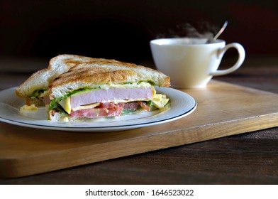 Sandwich Cheese And Thick Ham With Veg. In White Dish And Black Coffee All Put On Wooden Chopping Board 