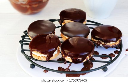 Sandwich cookies with chocolate ganache dripping on wire rack