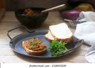 Sandwich with eggplant caviar, eggplant spread, bread and vegetables on a wooden background. Rustic style.