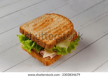 Sandwich with Ham, cheese, lettuce, and tomatoes inside of a loaf bread