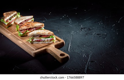 Sandwich With Ham, Cheese, Tomatoes, Lettuce, And Toasted Bread On Dark Background