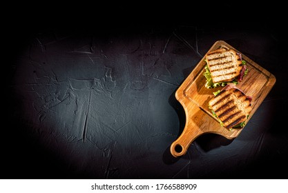 Sandwich With Ham, Cheese, Tomatoes, Lettuce, And Toasted Bread On Dark Background. Top View With Copy Space
