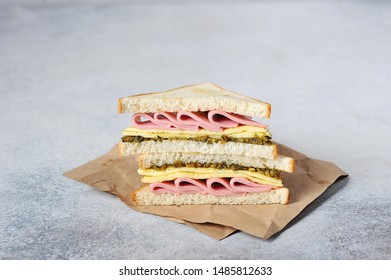 Sandwich with ham, scrambled eggs and pesto. Club sandwich on a sheet of kraft paper. Fast food concept. Light background. Close-up. Free space for text. - Powered by Shutterstock