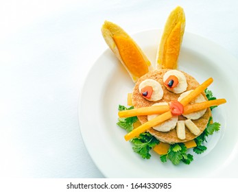 Sandwich Made And Garnished In The Shape Of Rabbit Face To Attract Children. The Sandwich Is Made Of Bred Slice, Papaya, Tomato, Banana And Coriander Leaf. It Is Placed In A White Plate.