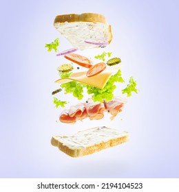 Sandwich On A Light Blue Background In Frozen Flight. Meat, Greens, Vegetables, Slices Of Bread. Fast Food. Advertising, Banner. There Are No People In The Photo.