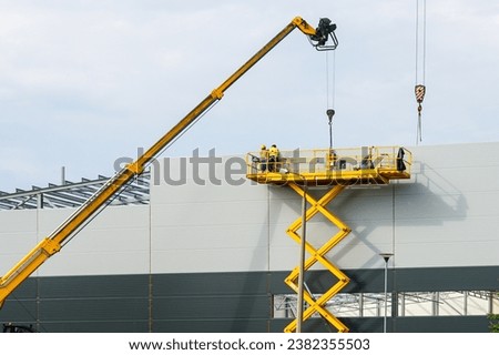 Sandwich panels wall assembly using telescopic boom crane and yellow self propelled scissor lift platform