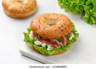 Sandwich with prosciutto, cream cheese and microgreens, bagel with ham, lettuce for breakfast on marble board. Space for text, close up. - Powered by Shutterstock