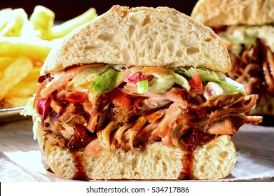 Sandwich with pulled pork, coleslaw salad dressing and a serving of fries. BBQ sauce