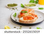 Sandwich with ricotta (cream cheese), smoked salmon and micro greens served on white background. Health care, super food concept.