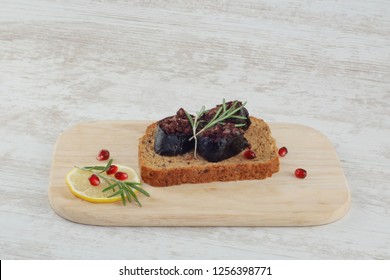 Sandwich with rye bread and sliced blood sausage on wooden plate