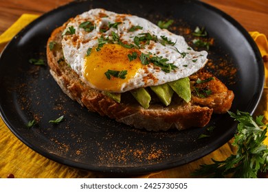 Sandwich with a slice of Italian bread, avocado and fried egg with runny yolk - Powered by Shutterstock