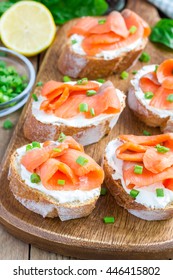 Sandwich with smoked salmon and cream cheese on wooden board, vertical