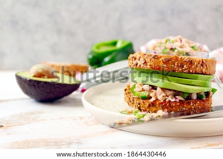 Sandwich with tuna, avocado and vegetables for snack or lunch. Top view with copy space. Healthy snack.