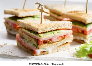 Sandwich of whole wheat bread with ham, cheese and fresh tomato, triangle cut, three layers sandwich bread - Powered by Shutterstock