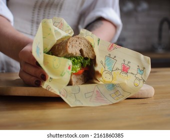 A Sandwich Wrapped In Wax Wrap In Female Hands