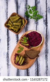 Sandwiches with beet and pickled cucumber on dark bread on a wooden background. Selective focus.