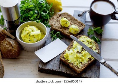 sandwiches for breakfast with homemade spiced  butter with lemon zest, turmeric, spices. rye bread and herbs on white wooden old table, copy space,