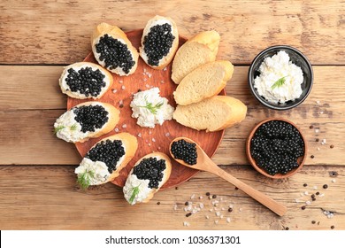 Sandwiches with delicious black caviar and cottage cheese on wooden plate