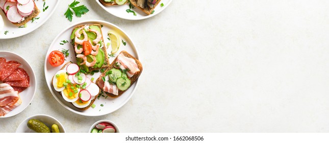 Sandwiches with meat, vegetables, seafood. Assortment open sandwiches on light stone background with free text space. Tasty healthy snack. Top view, flat lay. - Powered by Shutterstock