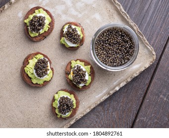 Sandwiches on Borodino bread with avocado paste, quail egg and black caviar