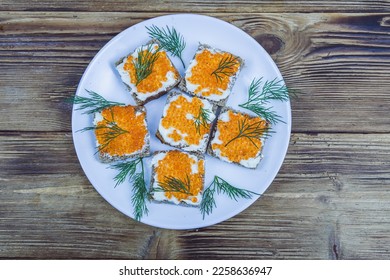 Sandwiches with red caviar on plate at wooden background. Top view - Shutterstock ID 2258636947