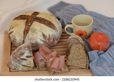 Sandwiches With Smoked Ham And Sliced Dark Bread.  Sourdough Loaf Of Wheat Bread With Whole Grain Flour And Sunflower Seeds. Crusty Whole Grain Loaf, Bread Slices, Coffee, And Kaki On Wooden Board.