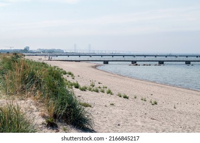 Sandy Beach With Blue Sea On The Coast Of Northern Europe In The City Of Malmo In Sweden. Piers Built Into The Sea.