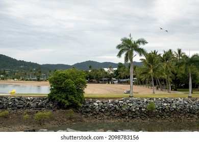 A Sandy Beach Bordered By A Rock Wall In The Small Australian Tourist Township Of Airlie Beach, Queensland